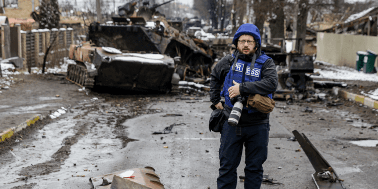 Photographer Serhii Nuzhnenko takes photos of a broken Russian convoy in Bucha near Kyiv, March 1, 2022. Photo: Stas Yurchenko / Graty