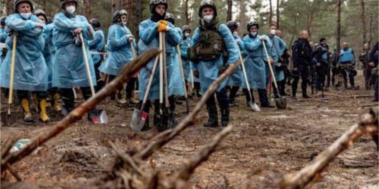 In this photo by Anton Skyba from The Globe and Mail, police officers holding shovels in front of an exhumation site at a makeshift cemetery in Izium, Ukraine, on September 16, 2022