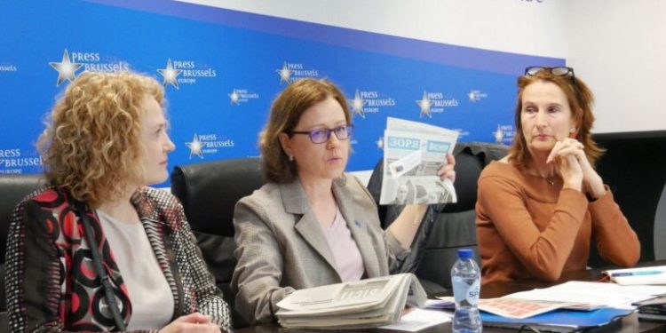 NUJU First Secretary Lina Kushch shows round table participants newspapers read near the front line