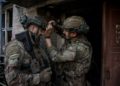 “Watching our videos makes the enemy surrender,” says Ivan Petrychak, 24th Brigade press service head 11 Press officer Ivan Petrychak adjusting the camera of the Skifa sniper before the combat exit, the central part of the city of Chasiv Yar, 2025. Photo by Oleh Petrasiuk.