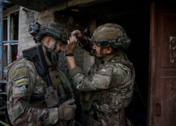 Press officer Ivan Petrychak adjusting the camera of the Skifa sniper before the combat exit, the central part of the city of Chasiv Yar, 2025. Photo by Oleh Petrasiuk.