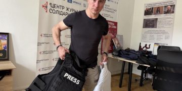 Dmytro Vlasov demonstrates the difference between a regular bulletproof vest used by journalists and an anti-fragmentation one. Photo by NUJU