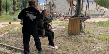 Sergiy Tomilenko: “Where the connection ends: the most dangerous newspaper route” 2 Nataliia Pasiuha, holding the Chuyka drone detector, sits on a swing in the frontline village of Spirne. Behind her lie the ruins of the café that served as a distribution point for Vorskla